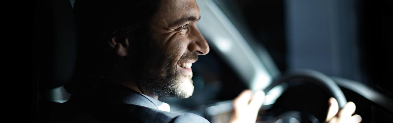  A smiling man sits in an Audi, firmly grasping the wheel.
