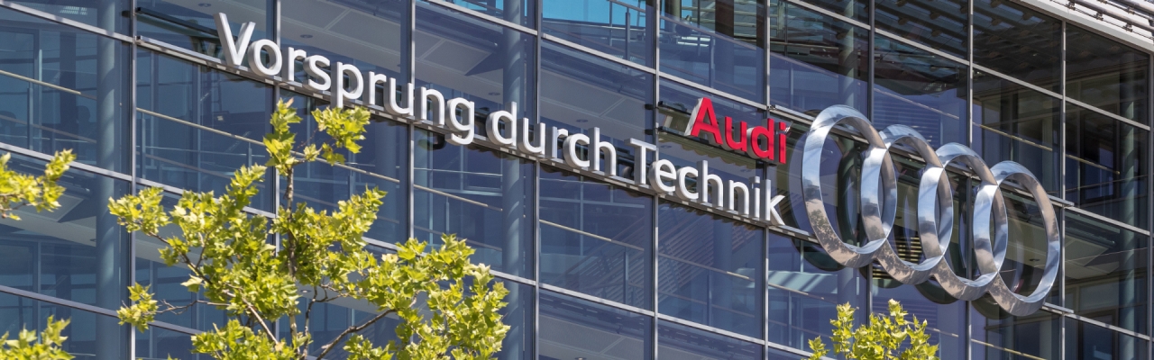  Gebäude von außen mit dem Audi Logo und dem Schriftzug „Vorsprung durch Technik“.