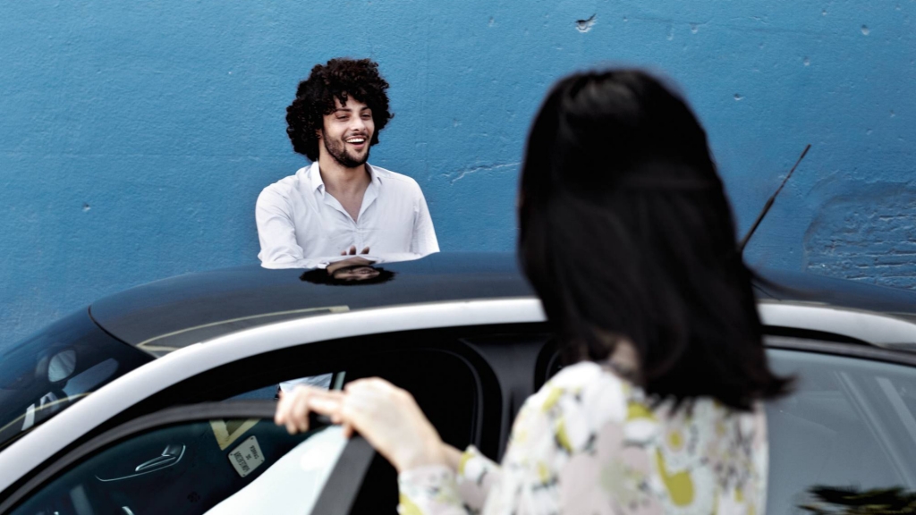 Ein junger Mann und eine junge Frau stehen neben dem Audi und haben die Türen geöffnet.